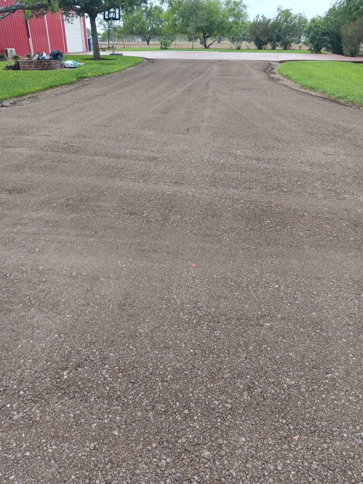 Long graded dirt driveway between grass