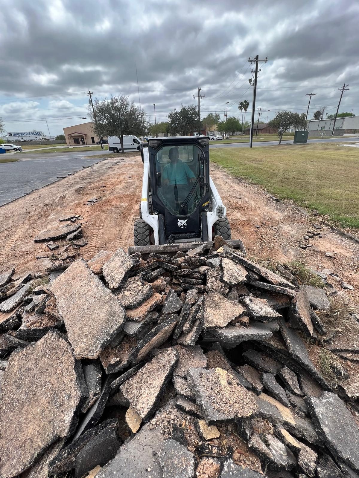 Skid steer pushing broken asphalt during road removal
